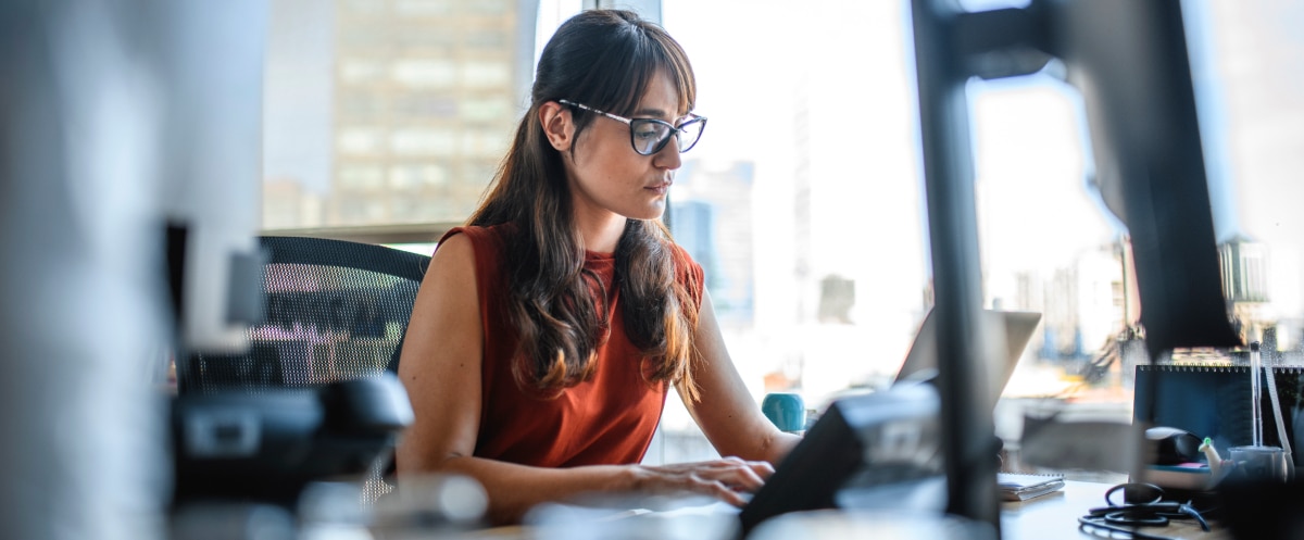 Professional using Microsoft 365 on a laptop at a modern office desk.