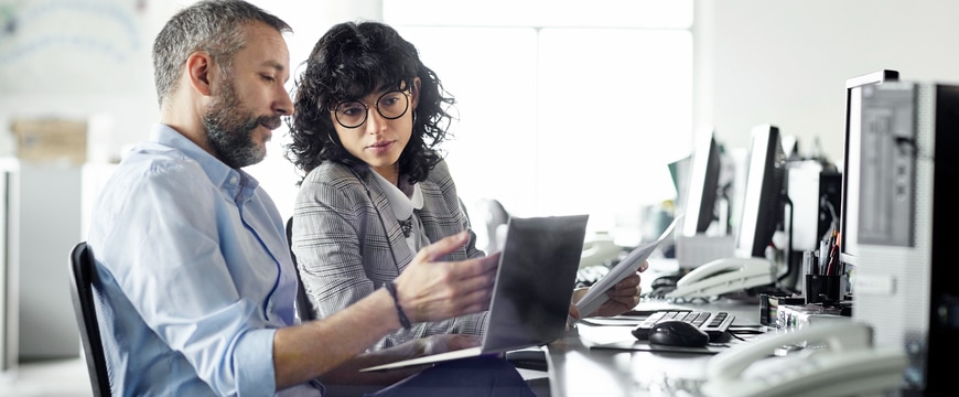 man and woman collaborating over laptop in office setting