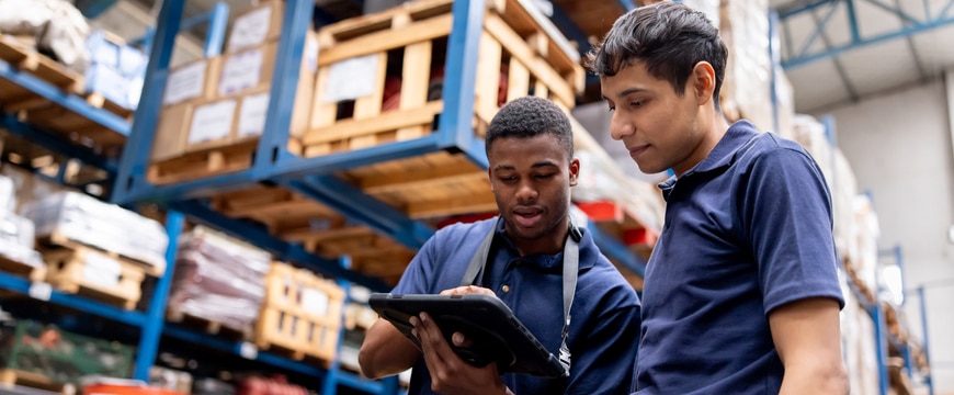 warehouse workers using rugged tablet for inventory and logistics operations on busy floor