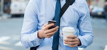 Guy looking at his phone and drinking coffee
