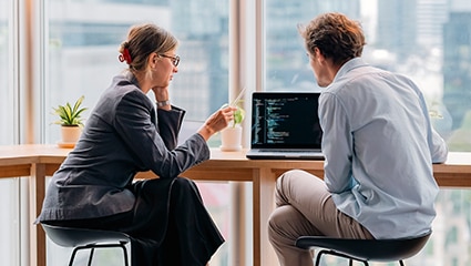 Two coworkers collaborating on code in bright office.