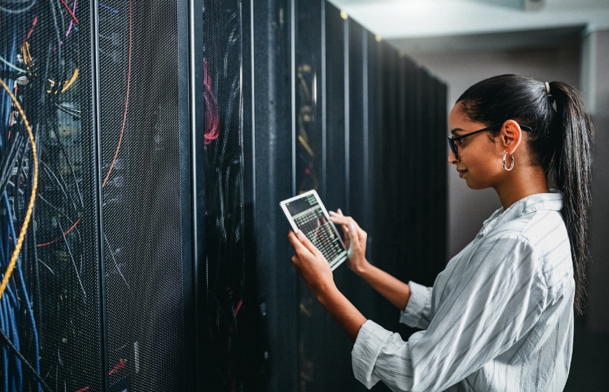 Close up image of a woman in server room using a tablet device.