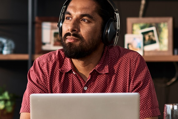 lifestyle image of a man wearing headphones working on a laptop computer