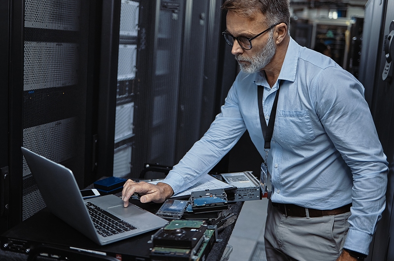 IT expert working on a computer in a server room.