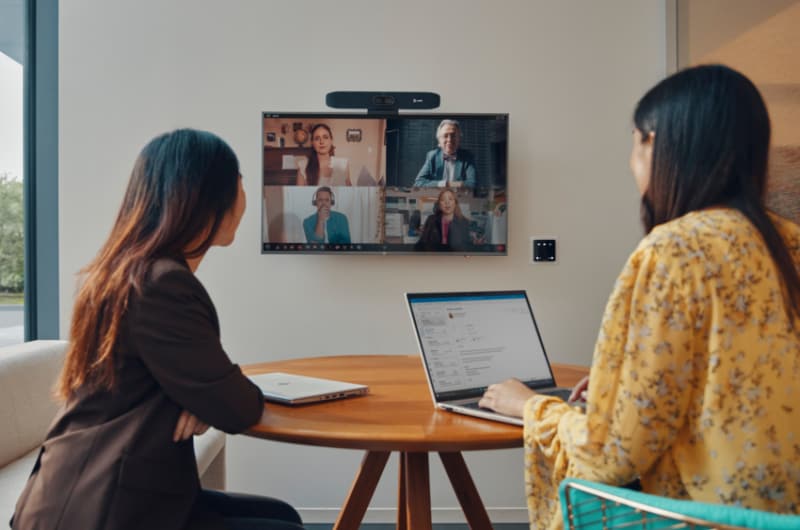 Two women are having a video conference on a large screen.