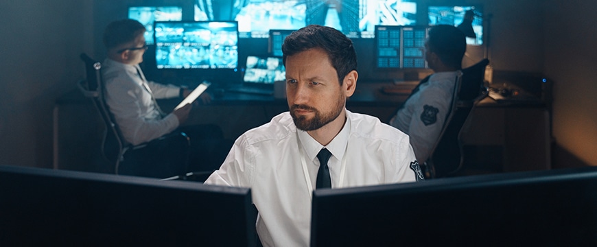 image of a security officer reviewing security footage on a monitor using AI tools