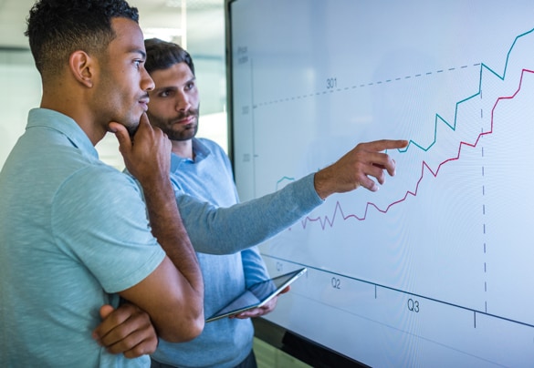 Two men reviewing data on a large touch screen display.