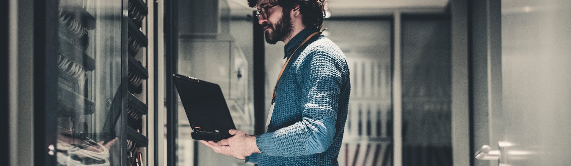 IT manager in server room using a laptop.