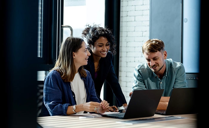 Team of professionals collaborating with laptops in a modern office, representing CDW’s technical expertise and innovative technology solutions that help businesses gain a competitive edge.