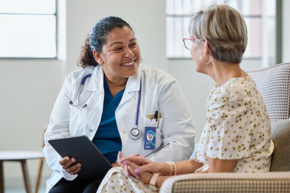 Female doctor reviewing patient data on tablet with a senior woman sitting beside her