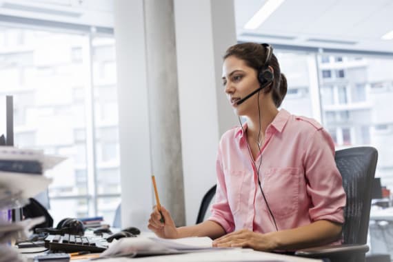 IT expert with hands-free device talking on telephone at office desk