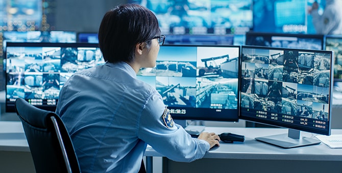 Image of security guard viewing security camera feeds at desk