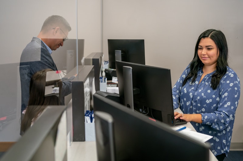 A government worker uses a computer to help a citizen at a Department of Motor Vehicles office.