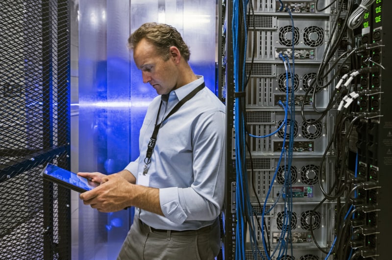 IT professional monitors server activity using a tablet in a data center.