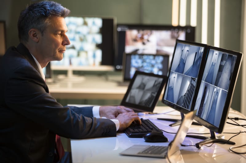 A security officer tracks activity on multiple computer screens.