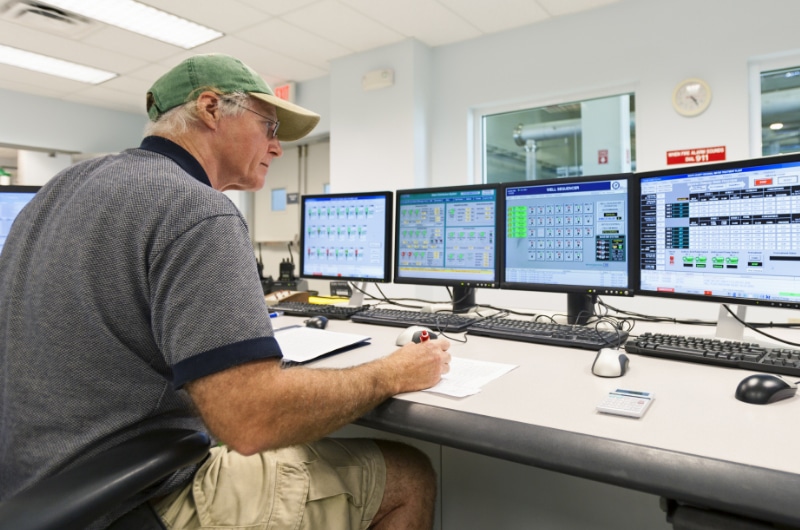 A rural government official is working on multiple computer screens.