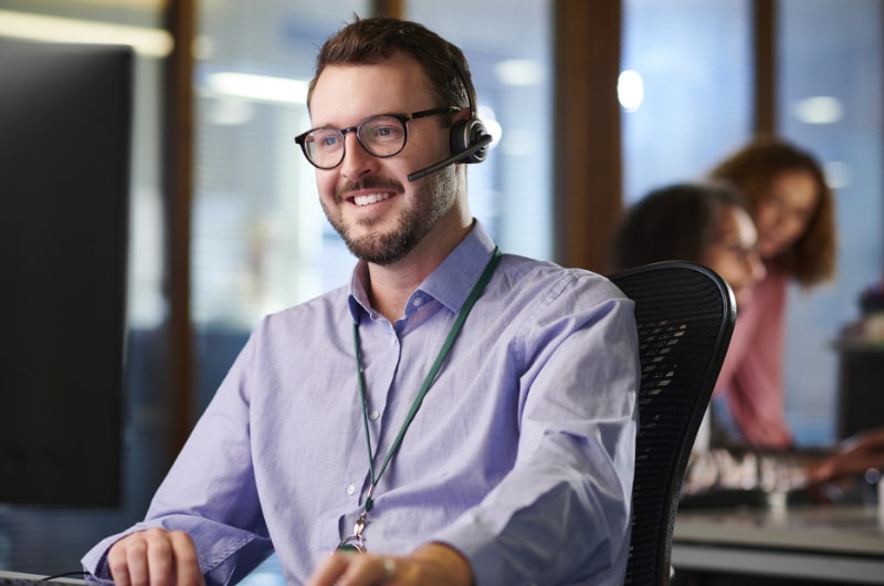 A tech support specialist uses a headset and computer to assist a customer over the phone.