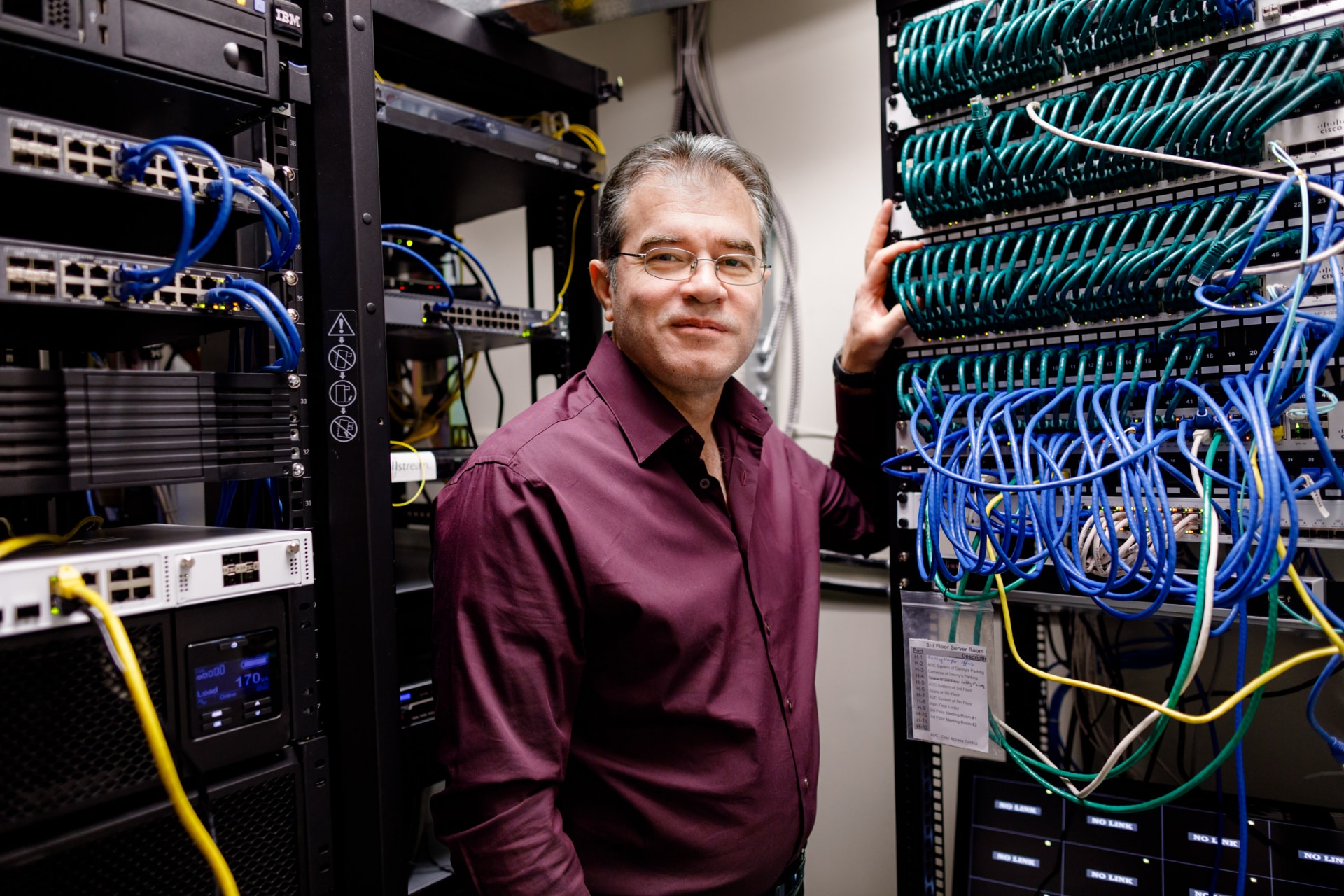 Person standing next to a networking server equipment.