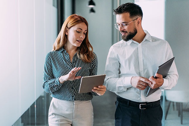 Professionals reviewing third-party risk assessments on a tablet while designing and executing a vendor risk management program.