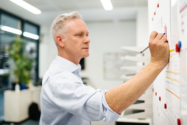 Government employee mapping out information on a whiteboard.