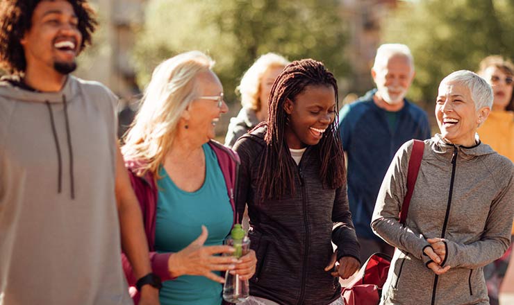 Four people laugh as they walk together holding water bottles
