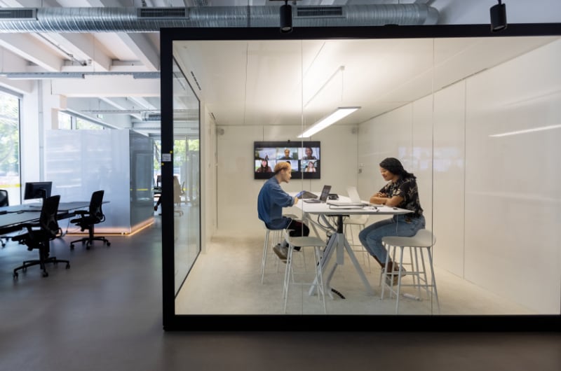 A team is having a video conference inside a modern office pod.