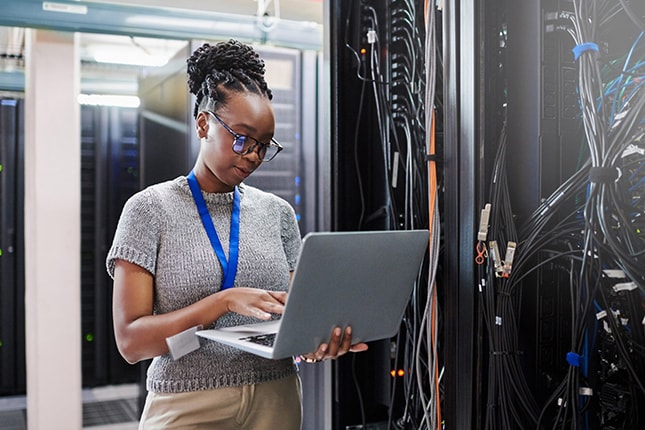 IT worker on laptop working in data center.