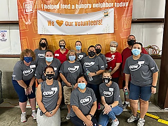 CDW coworkers pose in front of an orange volunteer banner at the Northern Illinois Food Bank