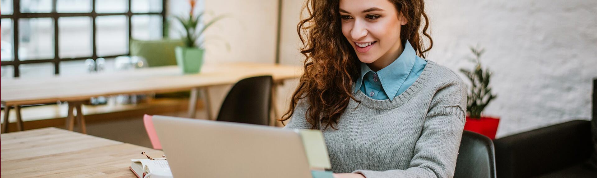 Lady working from home, smiling and looking at the laptop.