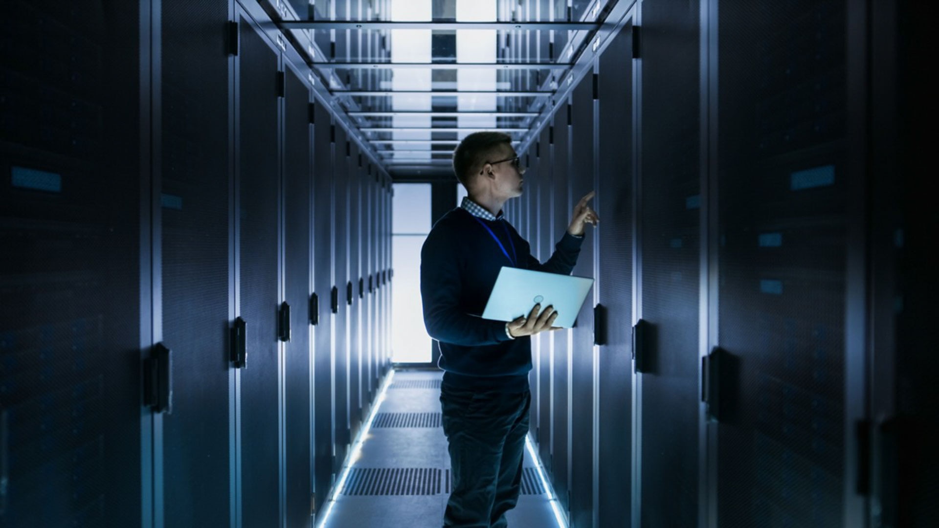 Person standing in data centre looking at a server rack.