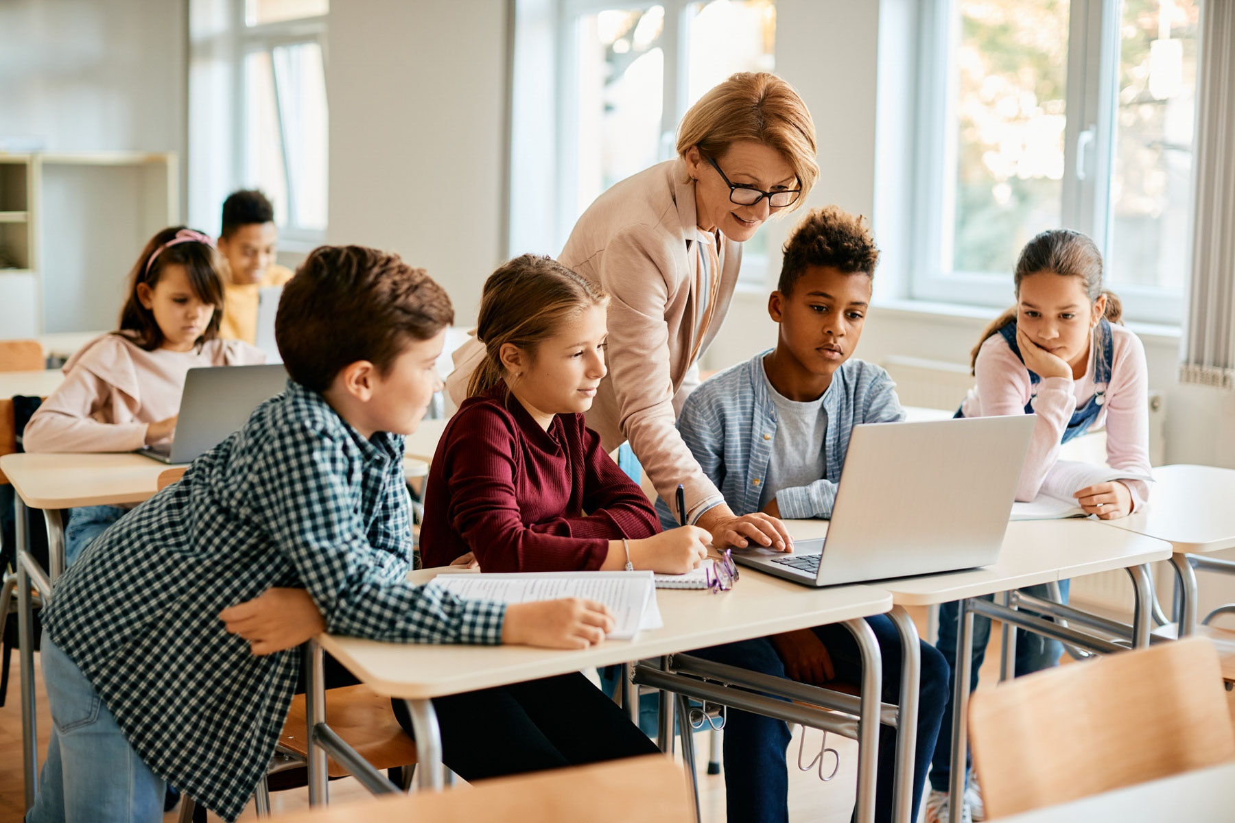 Teacher teaching students in a classroom using a computer.