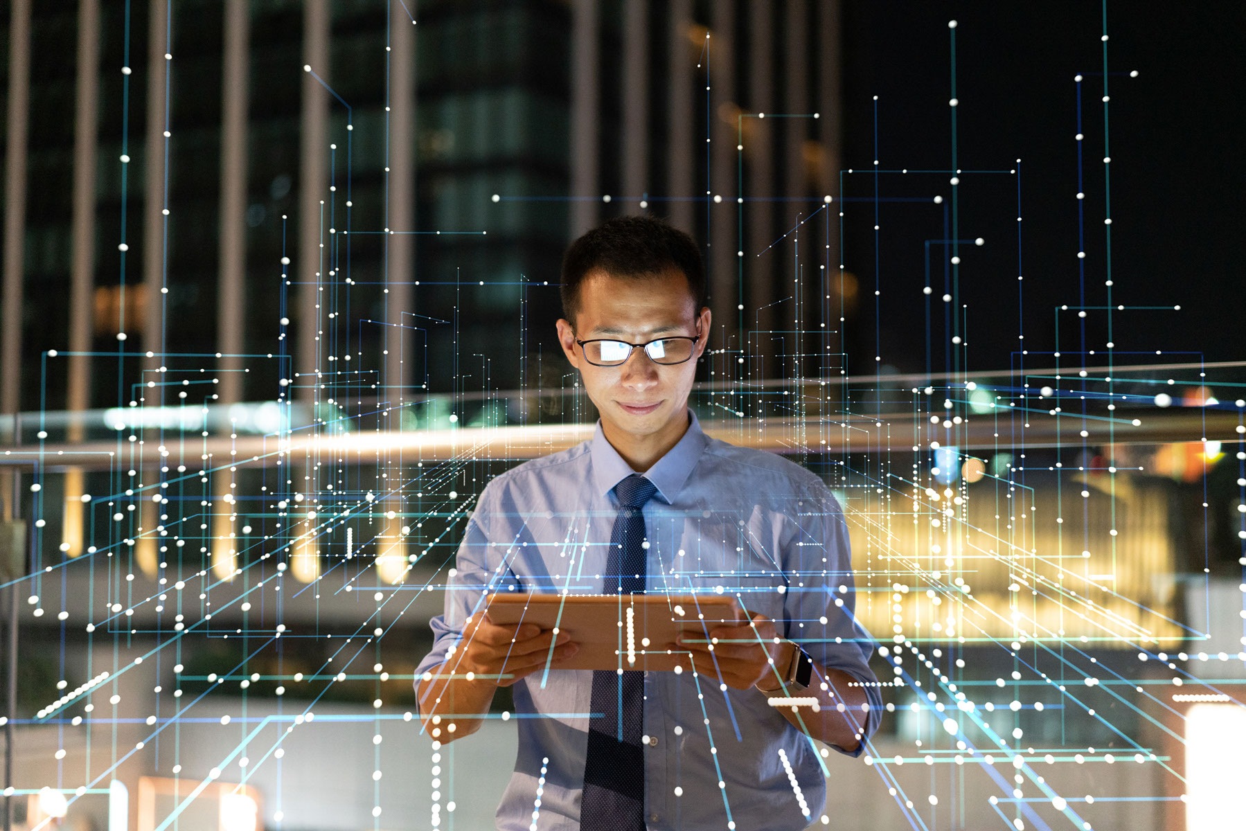 Person working on an iPad while standing on the sidewalk with a tall building in his background and overlay with geometric network visualization.