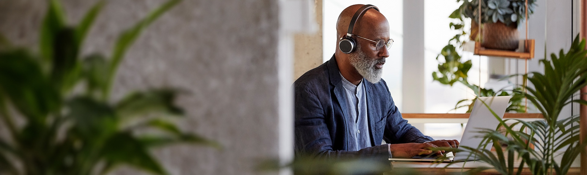 Person sitting on laptop with plants around him.